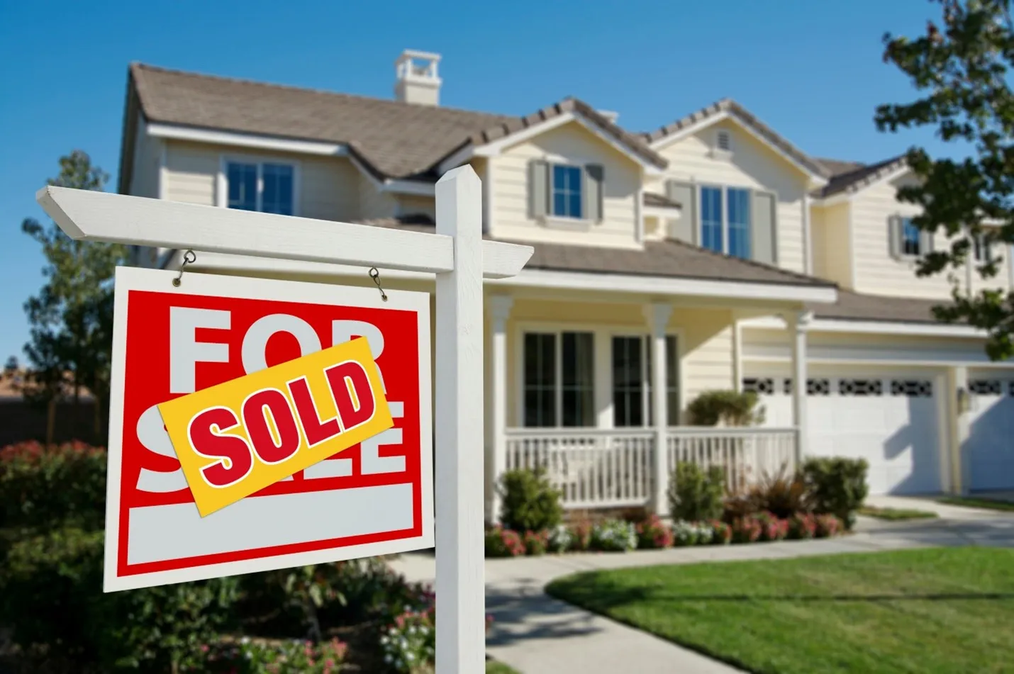 a larger suburban home with a sold sign in the front lawn