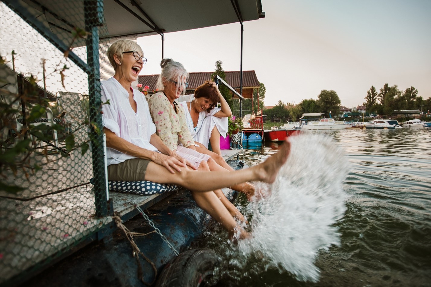 55 and older women kicking water by a dock while laughing about it.jpg
